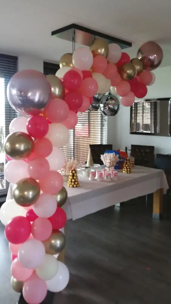Organische ballon slinger in de kleuren rose goud zilver wit en rood in een huiskamer